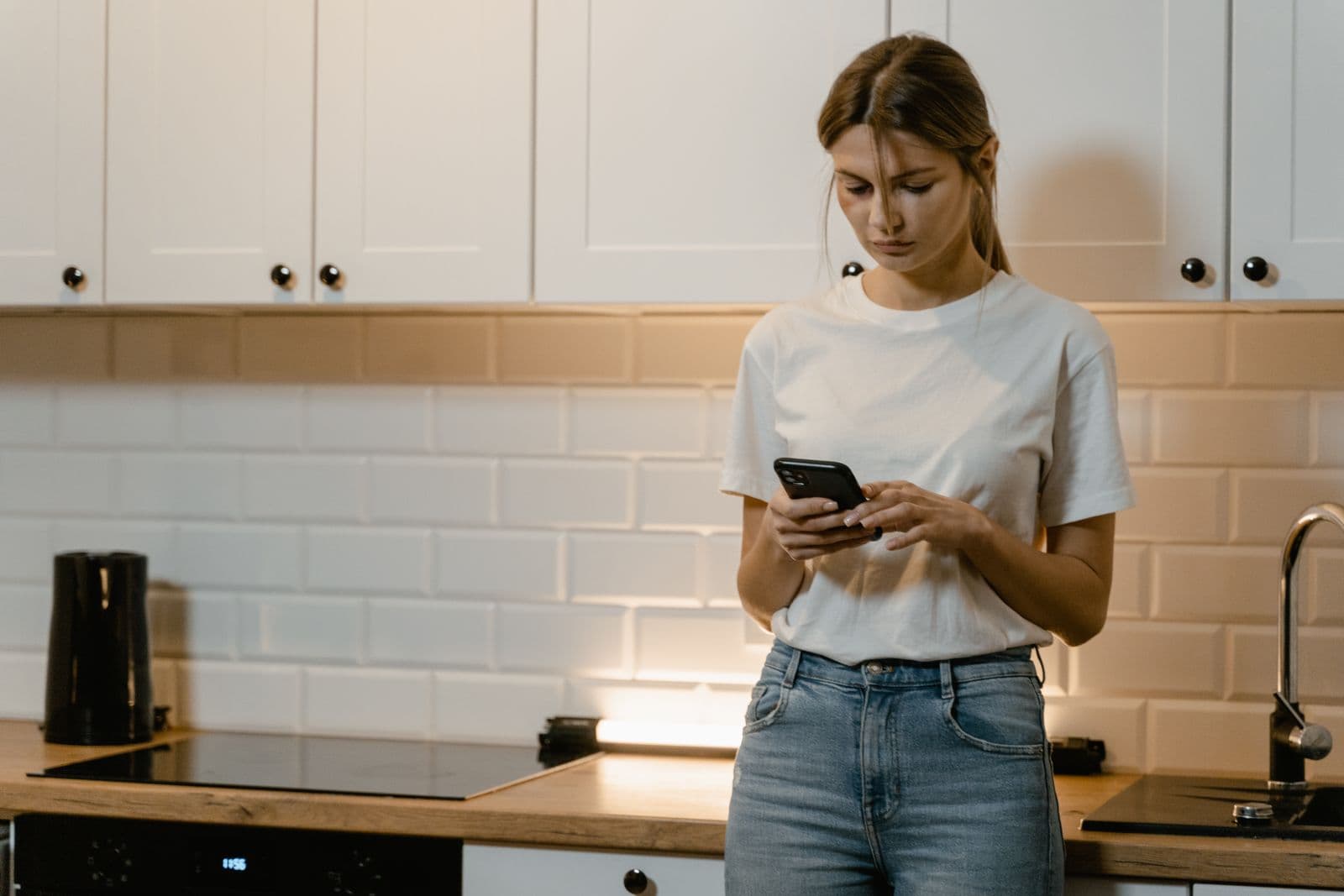 A woman using her phone in a kitchen