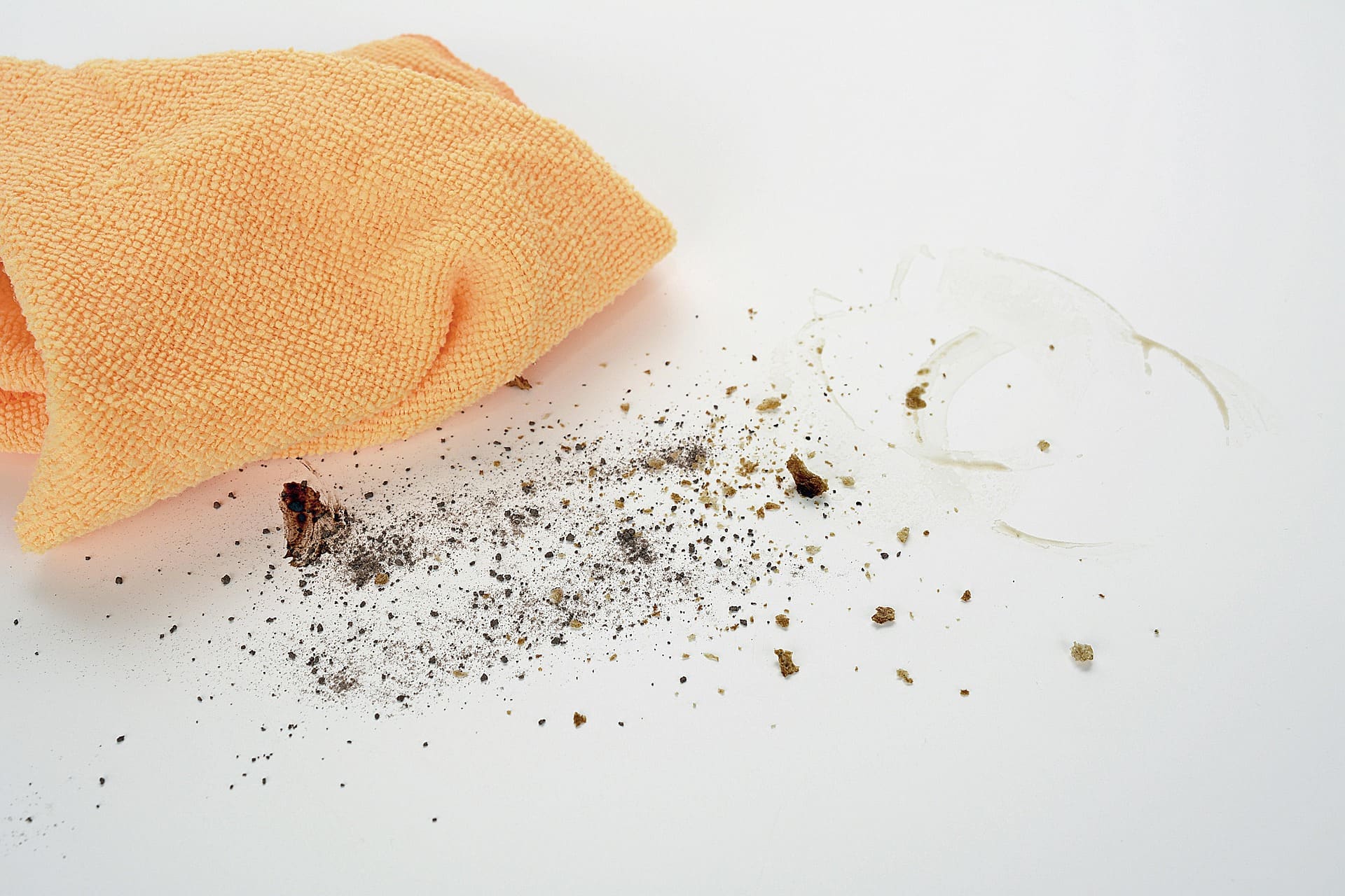 A microfiber cloth beside crumbs on a white counter