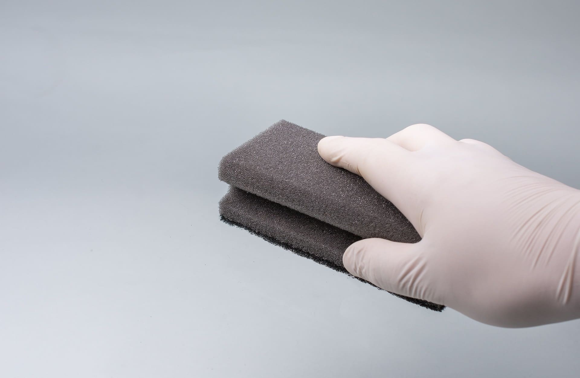 A gloved hand holding a cleaning sponge