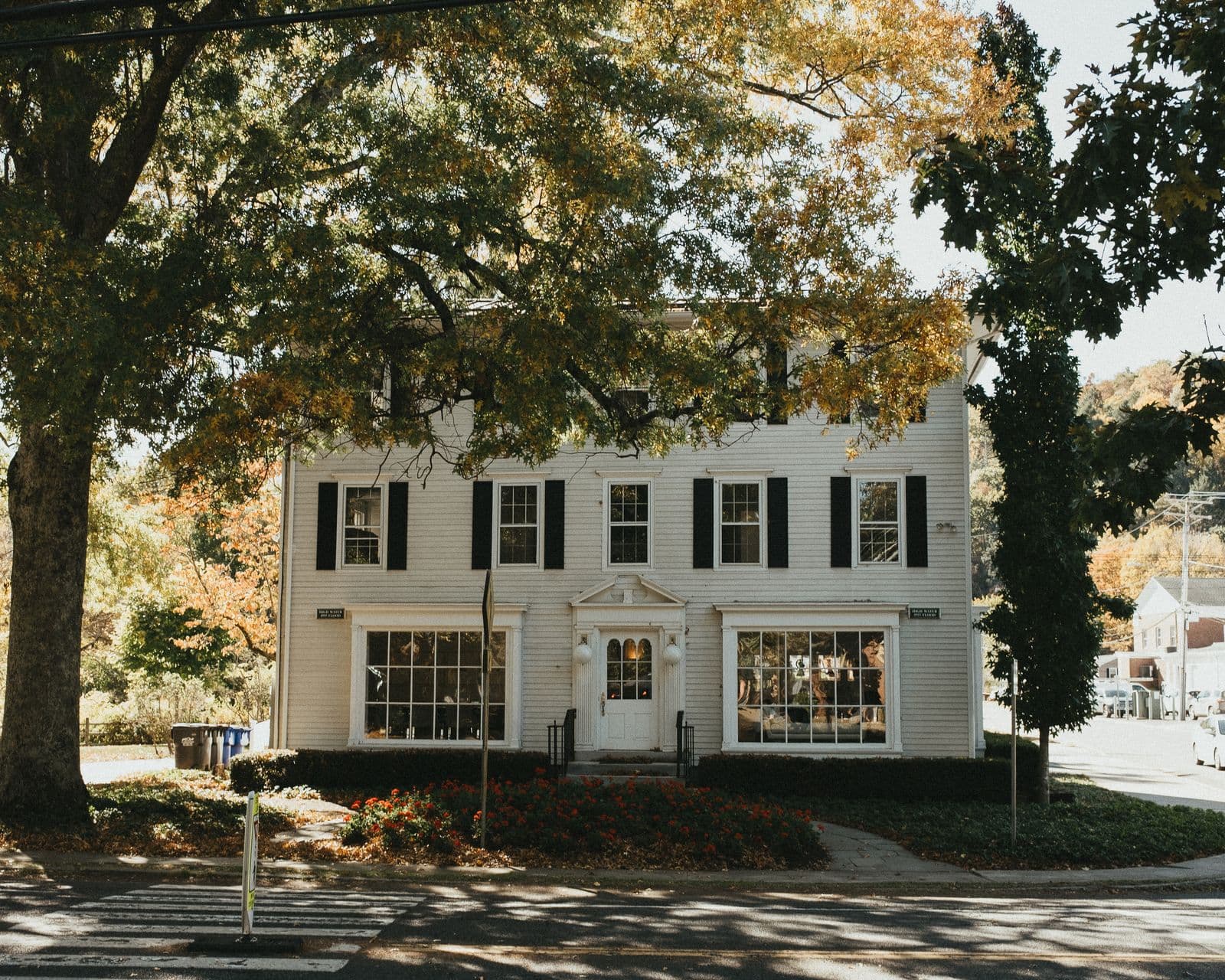 A white colonial-style building beneath autumn trees